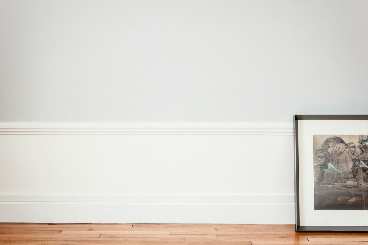 Tall white baseboard along a white wall above a wood floor.