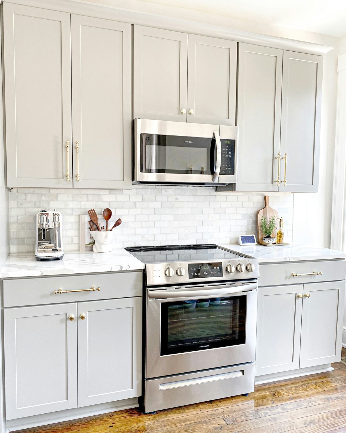 Kitchen with white shaker wall and base cabinets around a stainless range.