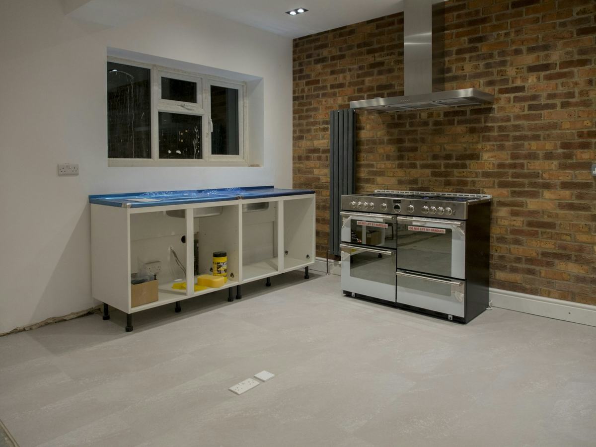 Kitchen under renovation with base cabinet boxes set in place along a wall before doors and countertop.