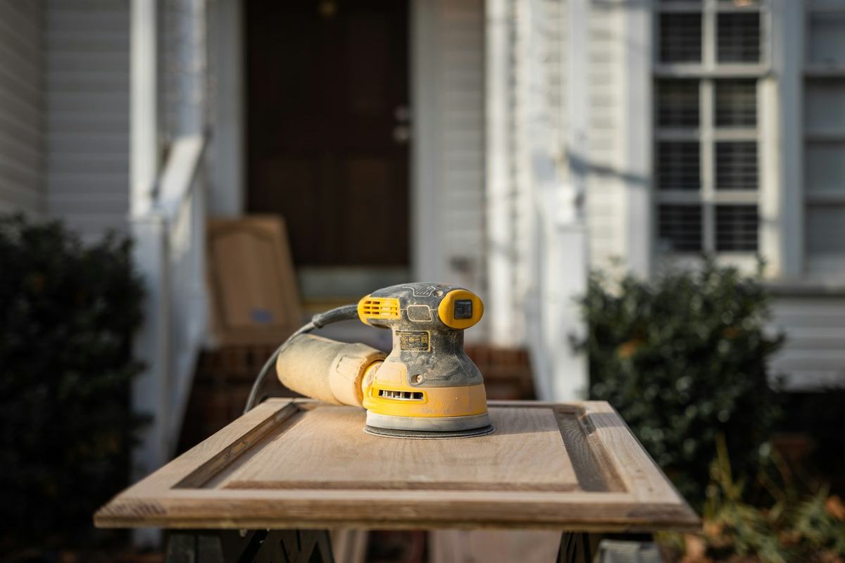 Orbital sander resting on a raised-panel cabinet door set on sawhorses.