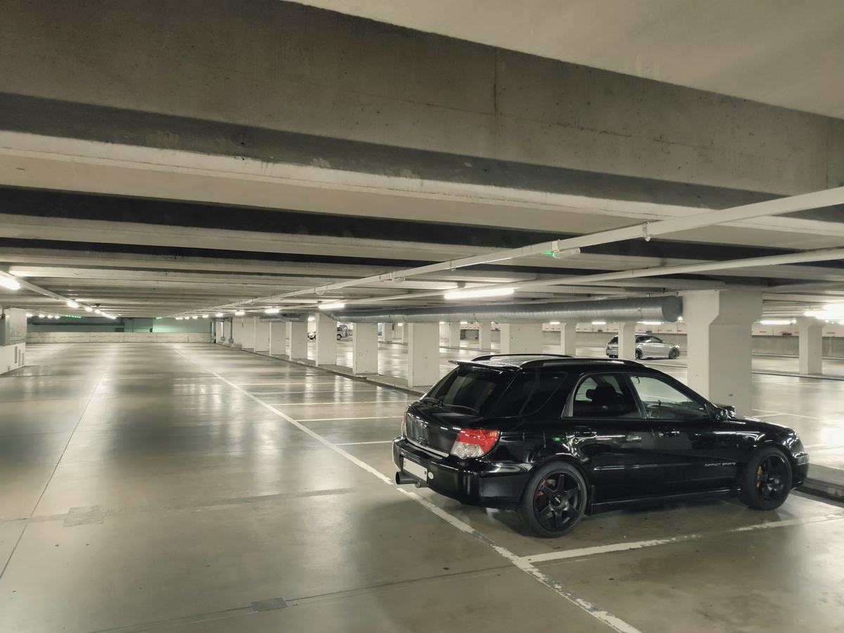 Parking level with a glossy light-colored coated floor and a single car.