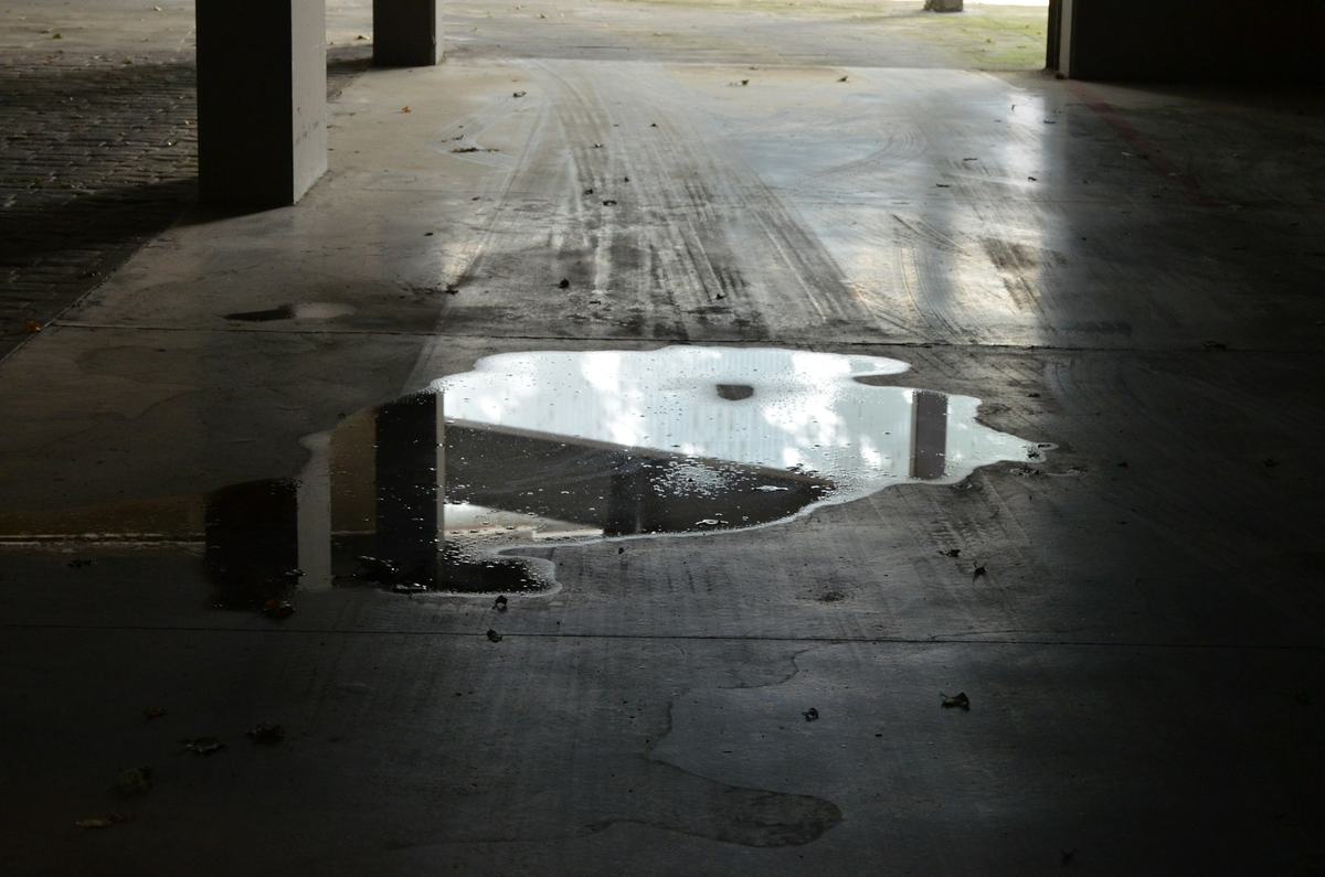 Standing water pooled on a concrete floor inside a covered structure.