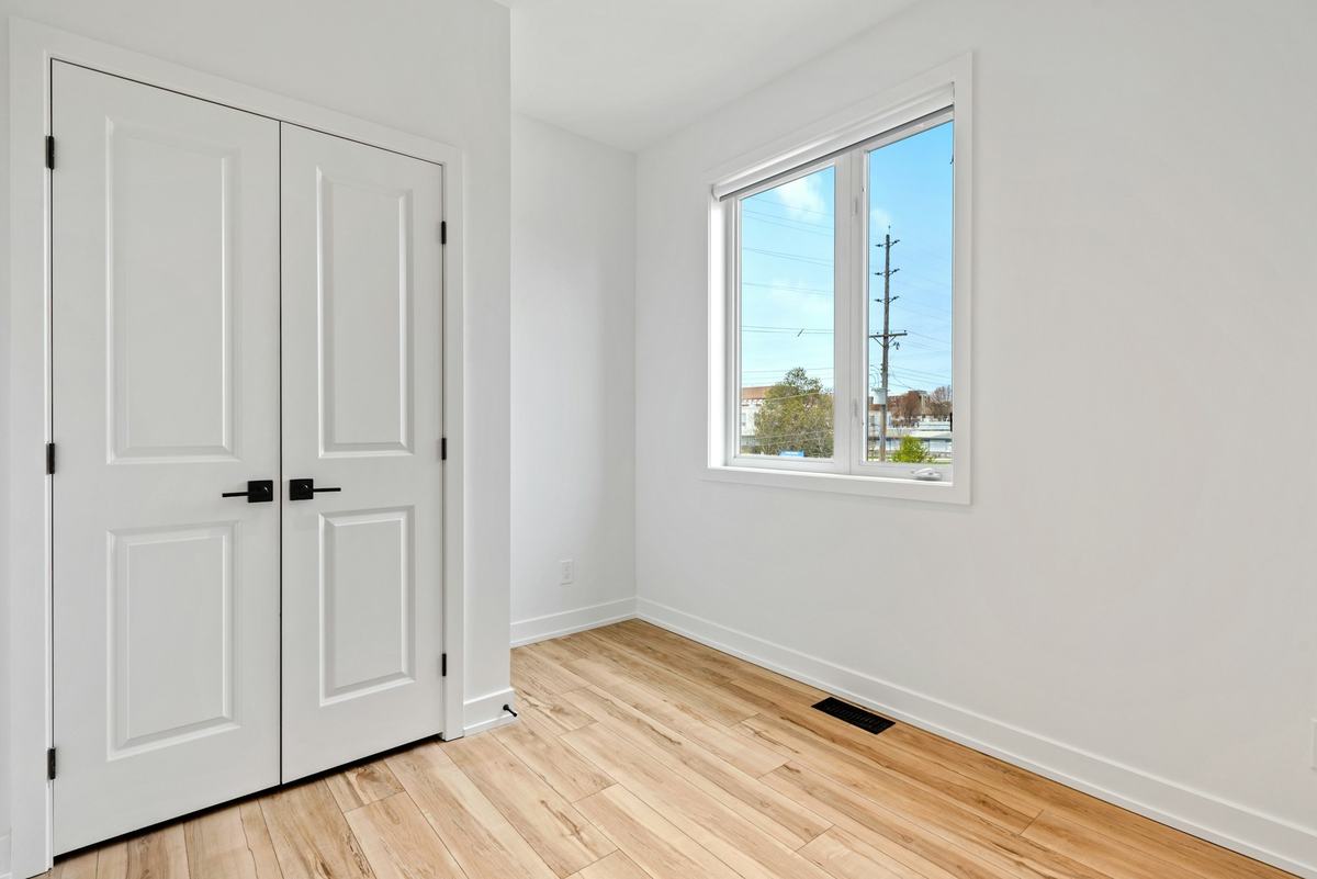 White double doors with black handles in a white room with a wood floor.