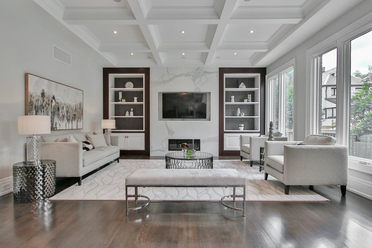Living room with a white coffered ceiling, white trim and built-in shelving.