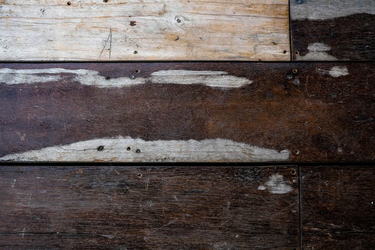 Old floorboards with strips of leftover adhesive after a floor covering was removed.