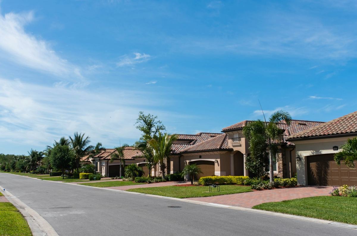 Residential street lined with tile-roofed homes, palm trees and lawns.