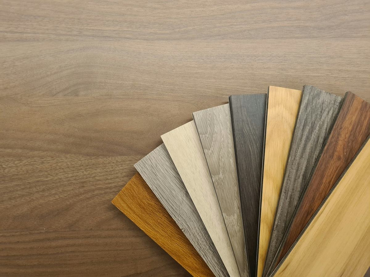 Fan of plank flooring samples in several wood tones laid on a floor.