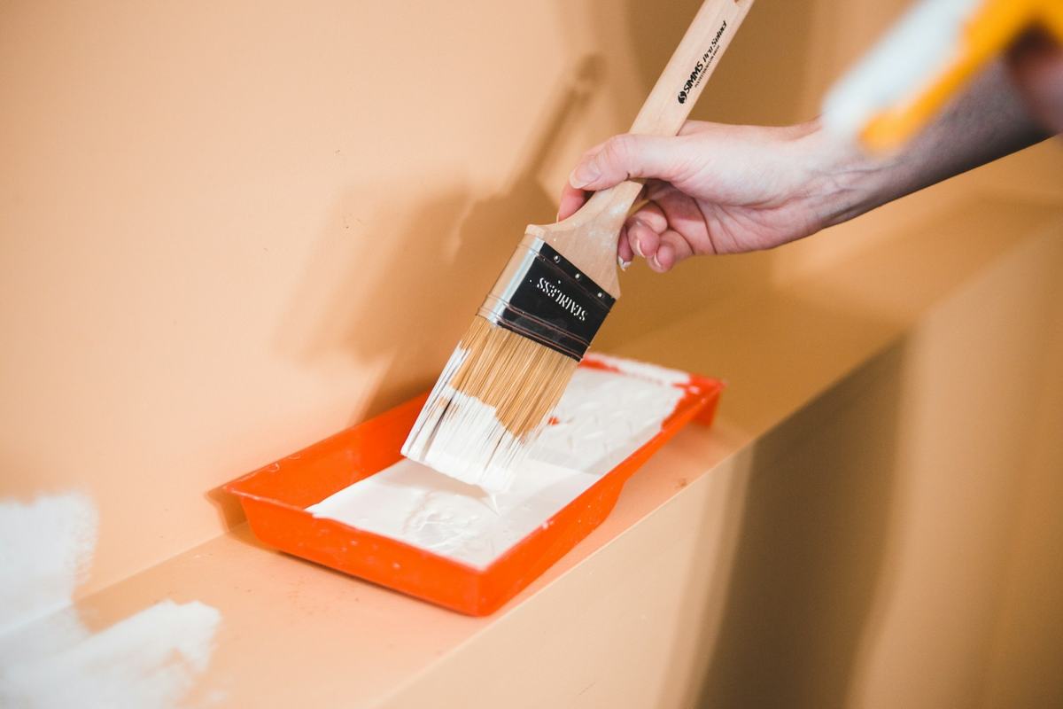 Hand loading an angled sash brush from a paint tray.