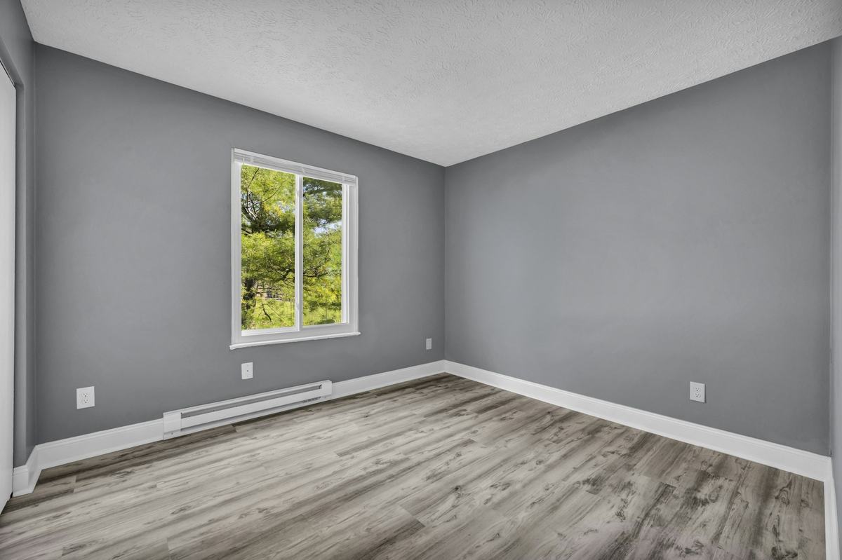 Empty bedroom with gray painted walls, white ceiling, white window trim and white baseboards.
